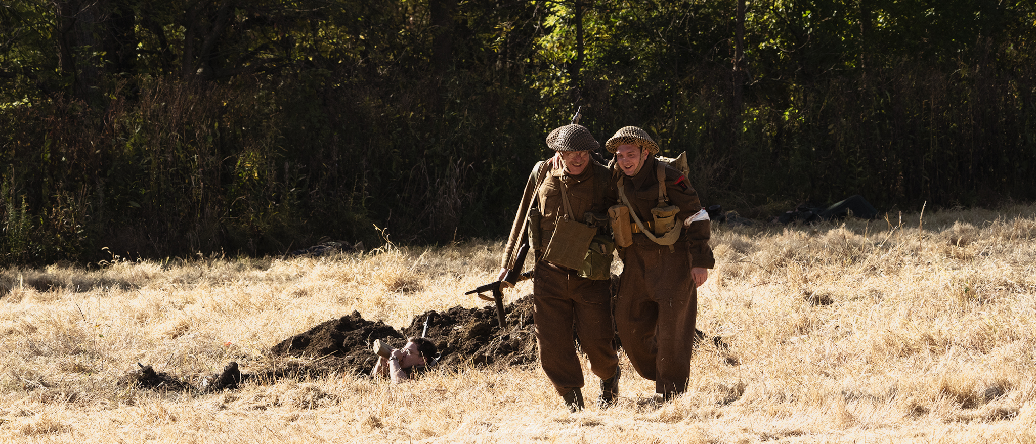 "Two World War II soldiers engaged in conversation as they walk across a grassy field, dressed in period-accurate military uniforms and gear. Their expressions convey camaraderie and a moment of respite amidst the turmoil of war. The backdrop features a landscape reflecting the era, possibly with trees or distant hills, and hints of a battlefield atmosphere, creating a poignant juxtaposition of friendship and conflict. This scene captures the humanity and bond between soldiers during one of history's most challenging times."